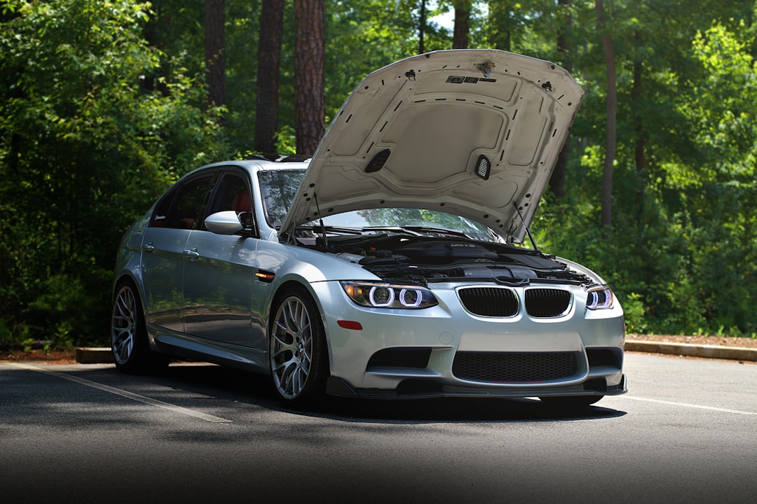 A silver BMW with its hood open.