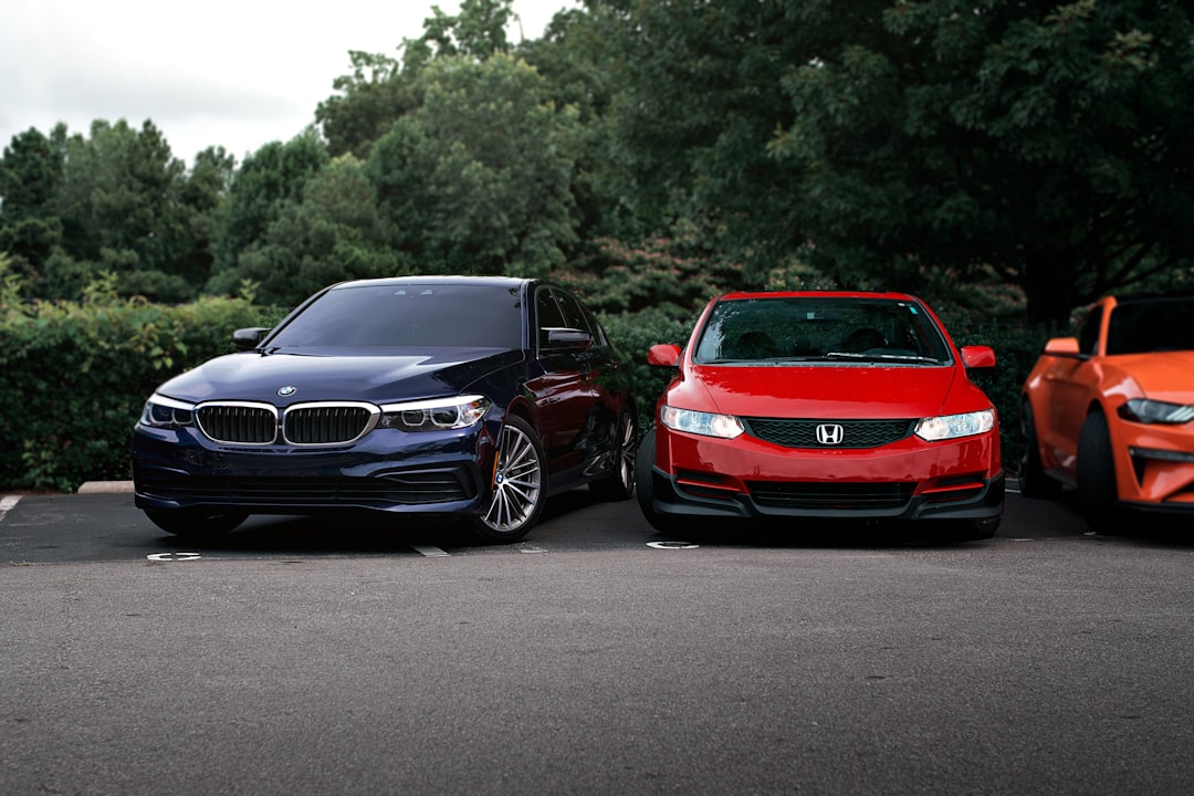 Three cars are parked in front of trees.