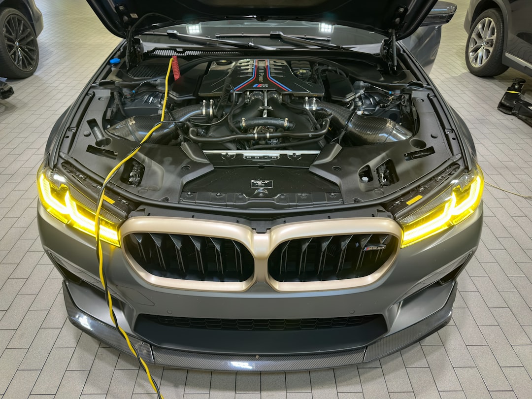 a silver car with its hood open and a yellow wire connected to it