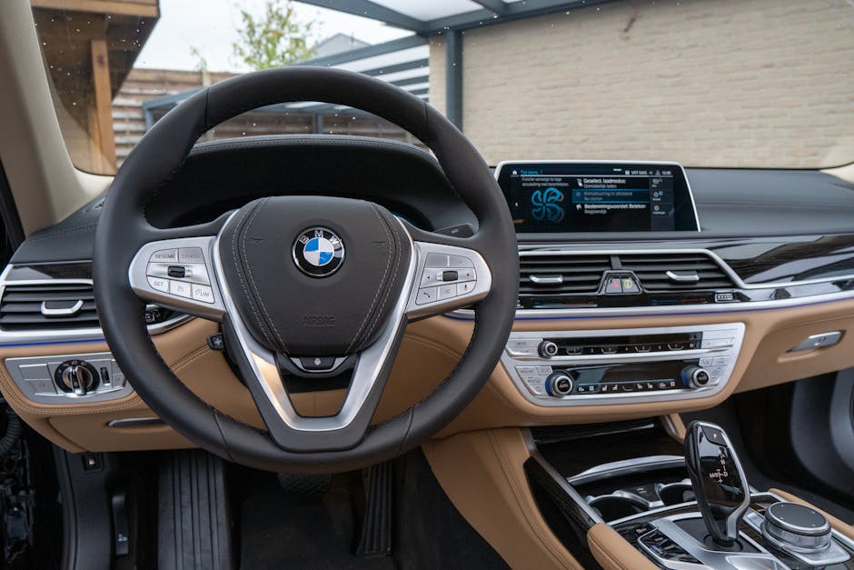 Elegant car interior featuring a leather steering wheel, dashboard, and high-tech controls.
