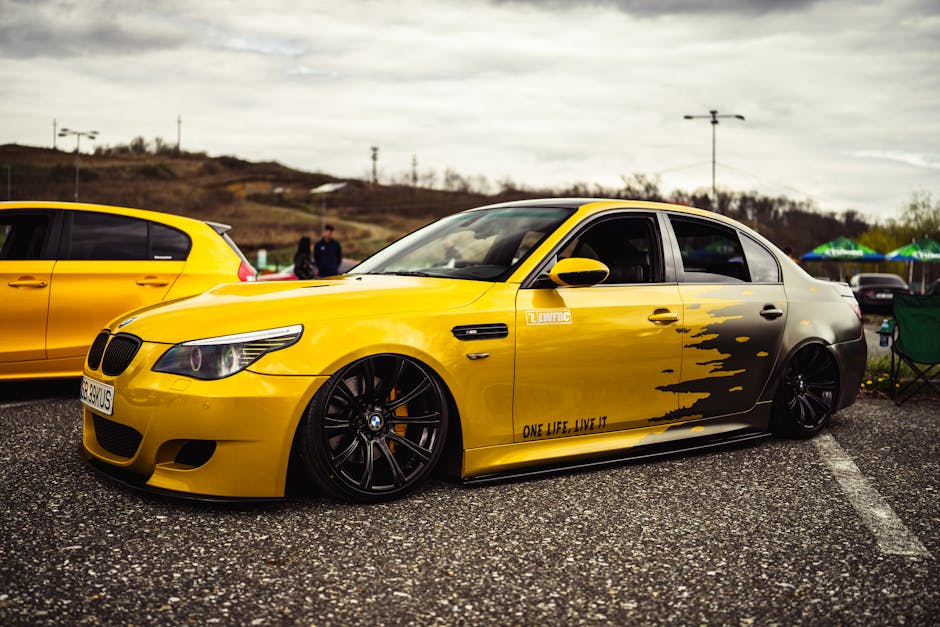 A sleek yellow BMW sedan parked outdoors showcasing custom modifications and dramatic styling.