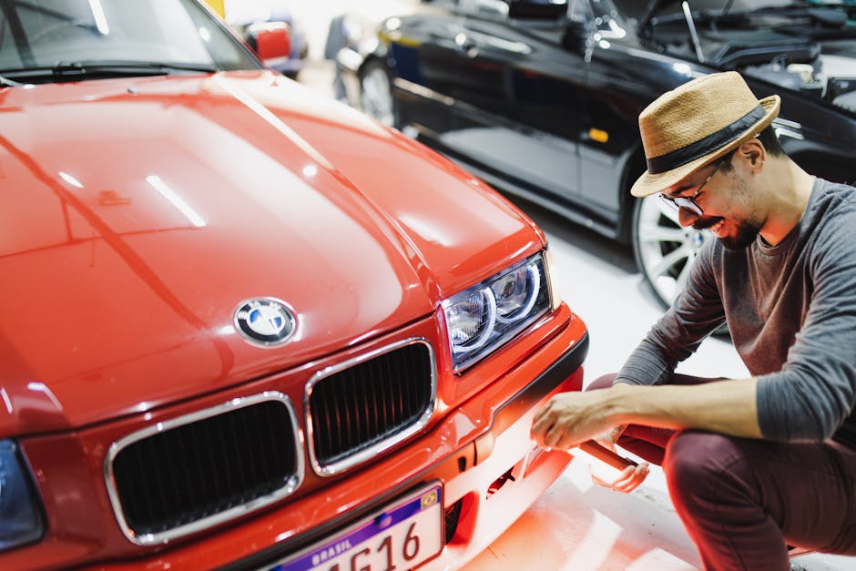 Smiling man with hat admires a retro red BMW car in an indoor showroom setting.